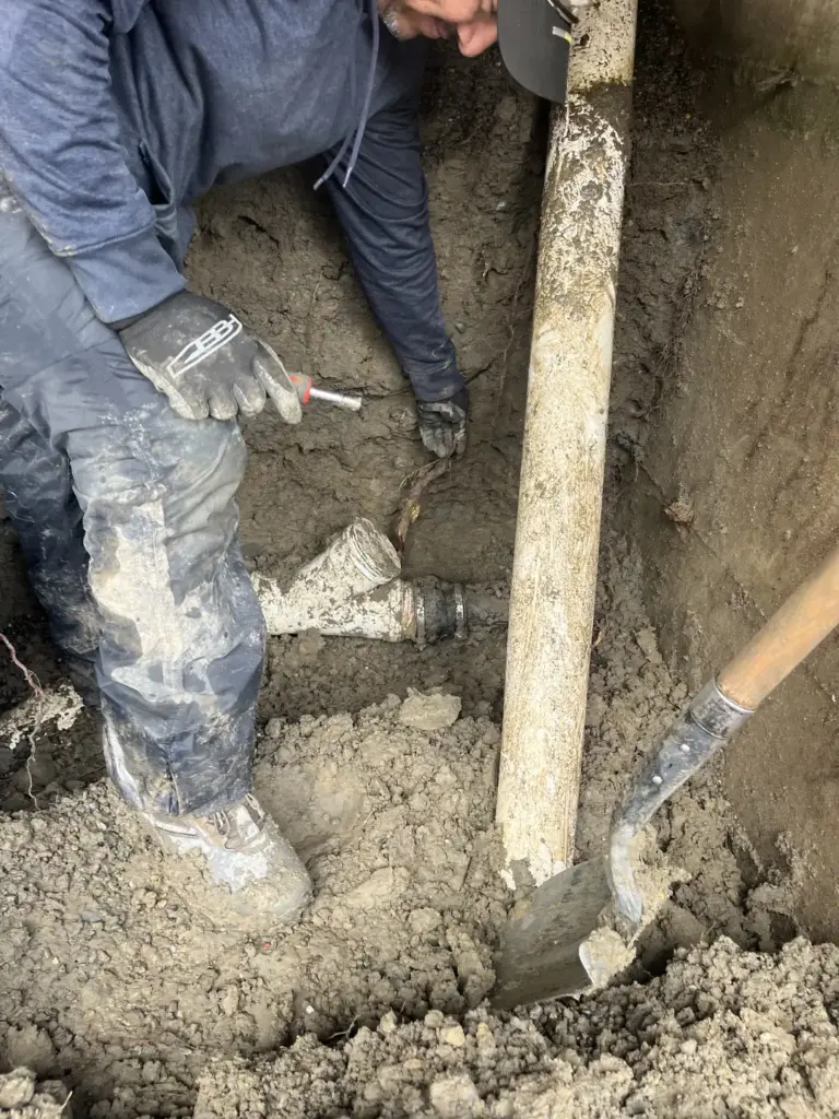 Person clearing a drain in dirt.