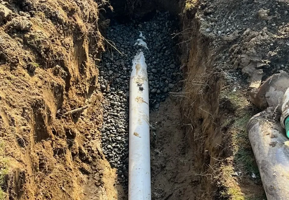 Excavated trench with sewer pipe visible.